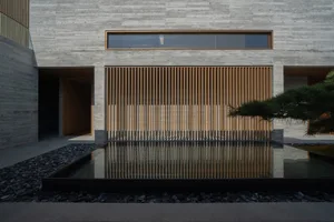 A modern outdoor space featuring concrete walls, wooden slats, and a water feature.