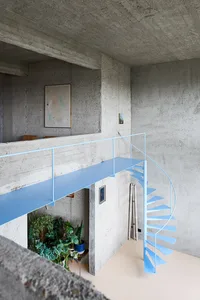 A modern industrial staircase with blue steel steps and railings against a concrete wall.