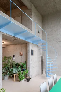 A modern loft space featuring a metal staircase, industrial design elements, and natural light.