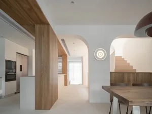 Modern minimalist dining room with wooden furniture and white walls.