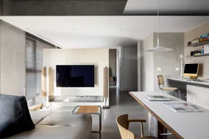 A modern, minimally styled living room with concrete tiles, a sleek sofa, and minimal furnishings.
