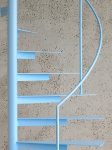 Modern minimalist blue metal spiral staircase with a light-colored, speckled wall background.
