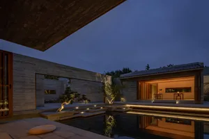 A modern residential exterior with concrete walls and glass elements.