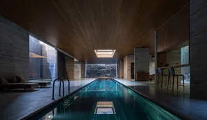 Modern swimming pool with concrete interior and glass walls, featuring a sleek, minimalist design.