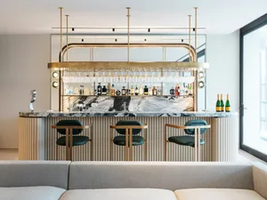 Modern interior bar featuring a marble counter with brass accents and upholstered seating.