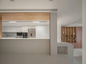 A modern kitchen with white walls and a white countertop, featuring a wooden ceiling and a wooden column.