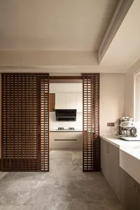 Modern kitchen with wooden lattice divider and marble countertops.