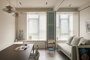 A modern minimalist living room with neutral colors, featuring a white sofa, a wooden coffee table, and a kitchen area with w