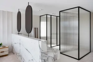 Modern minimalist bathroom with white marble and glass features, black accents, and a frosted glass shower enclosure.