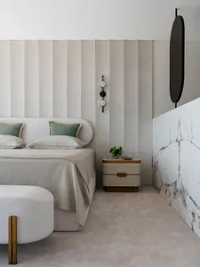A modern bedroom featuring a neutral-toned color palette, plush bedding, and minimalist decor.