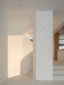Modern white concrete staircase with minimalist design, featuring a wall clock and pendant lights.