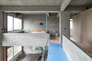 A minimalist bedroom with concrete walls and a loft-style bed.