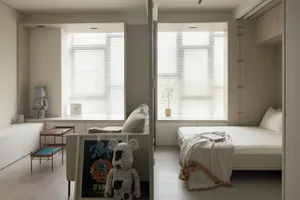 A minimalist bedroom with a bed, couch, and window with blinds. Room features a neutral color palette and simple furnishings.