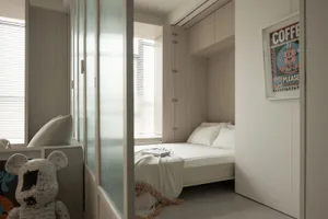 A minimalist bedroom with a wooden bed, white bedding, and textured fabric pillows.