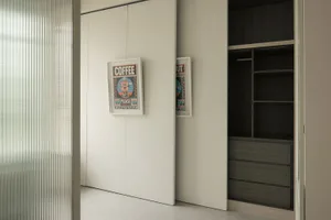 Minimalist modern closet with white sliding doors and black minimalist design, featuring framed posters.