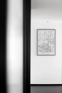 A minimalist black framed paper map on a white wall in a hallway.