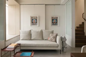 Minimalist living room with neutral-colored furniture and posters on the wall.