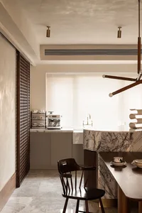 Modern residential kitchen featuring marble countertops, wooden cabinets, and metallic accents.