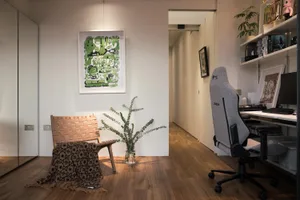 A modern, minimalist home office featuring a wooden chair and a desk with a computer.