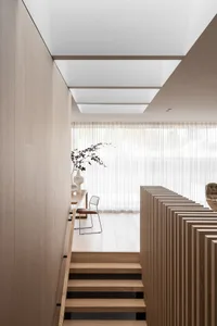 Modern minimalist living space featuring wooden stairs and neutral tones.