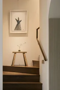 A minimalist staircase with a wooden stool displaying a small indoor plant.