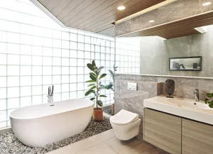Modern bathroom featuring a freestanding bathtub, a wall-mounted toilet, a floating vanity with a sink, and a large window wi