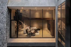 Contemporary living room with concrete walls and floor, featuring minimalist furniture and a cozy atmosphere.