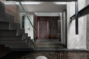 Modern entrance featuring a concrete staircase and wooden door with a stone wall in the background.