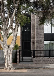 A modern residential facade featuring gray brick walls and black framed windows.