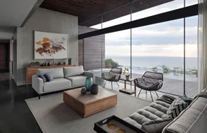 Modern living room featuring a sleek concrete floor and large windows overlooking the ocean.