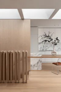 A modern minimalist kitchen with marble countertops and wooden cabinets.