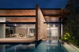 Modern residential exterior featuring wooden walls and a large pool.