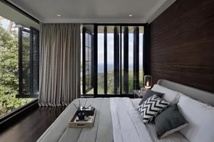 A minimalist bedroom featuring taupe and gray tones, with a bed, pillows, and a tray on the bed.