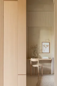 A minimalist office with a wooden wall, chair, and small desk.