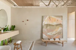 A modern bathroom featuring a concrete floor, minimalist design, and a large abstract painting on the wall.