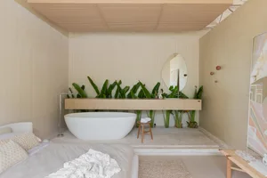 A modern bathroom featuring a freestanding bathtub, a wooden vanity with green plants, and a minimalist design.