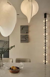 A modern dining room with a marble table and chairs, featuring minimalist design and elegant lighting fixtures.
