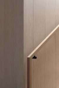 Modern, minimalist wood stair railing with a sleek, horizontal design against a light wooden wall.