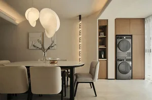 A modern minimalist dining room with a round table, white pendant lights, and wooden cabinets.