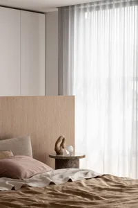 A minimalist bedroom with a wooden bed and glass curtain, featuring a small sculpture and an upholstered headboard.