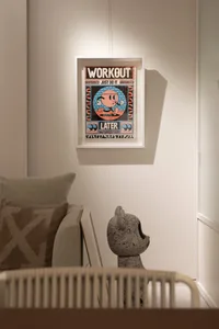 A minimalist poster with a cartoon character and the text 'Workout Later', framed and hung on a wall.