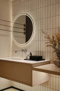 Modern bathroom design featuring a circular mirror and a sink with ceramic tiles on the walls.