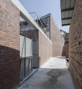 Modern brick building exterior with a concrete walkway and a glass window.