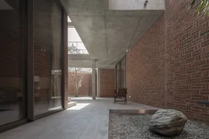Modern industrial-style loft with exposed concrete ceiling, brick walls, and a concrete floor, featuring minimalist furniture