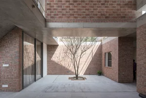Modern interior space featuring brick walls and a tree in a courtyard.