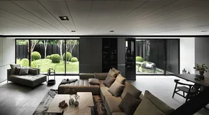 Modern living room with glass windows, a leather sofa, and wooden accents