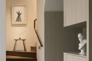 Modern minimalist living room featuring wood and concrete materials, with a plant and artwork as decorative elements.