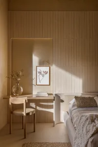 A minimalistic bedroom with wooden paneling, a bed, a side table, and a framed art piece.
