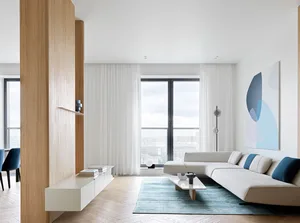 A modern, minimalist living room featuring open space, large windows with city view, wooden columns, and a grey sectional sof