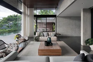A modern living room with concrete and wood materials, featuring a comfortable sofa, a minimalist coffee table, and large win